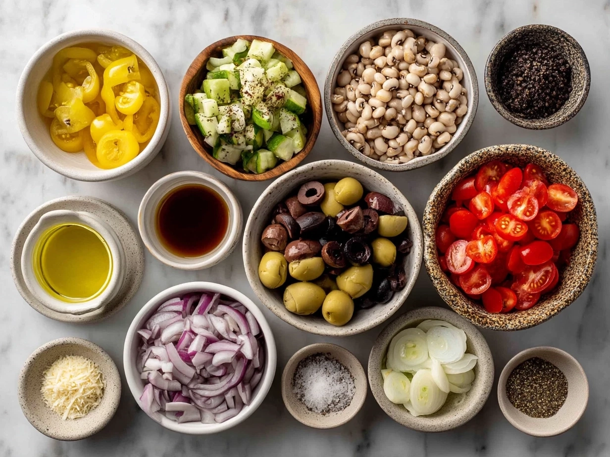 Top down view of raw ingredients including black eyed peas, olives, cucumber, red bell pepper, onion, lemon and herbs for Olive Salad with Black Eyed Peas